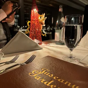 a table setting with a menu and a glass of wine