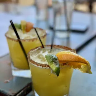 two cocktails with orange slices and garnish