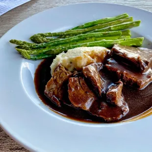 a plate of meat with mashed potatoes and asparagus