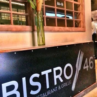 a restaurant sign with a vase of flowers