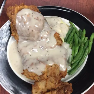 a plate of fried chicken with gravy and green beans