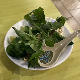 a plate of fresh herbs and a spoon