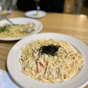 two plates of pasta and a glass of wine