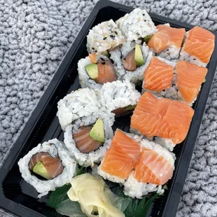 a tray of sushi with salmon and avocado