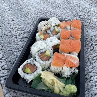 a tray of sushi with salmon and avocado