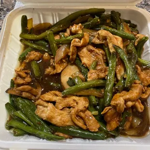 a chicken and green beans dish in a styrofoam container