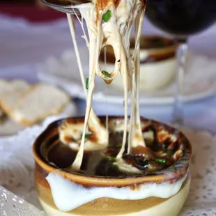 a person dipping cheese into a bowl of soup