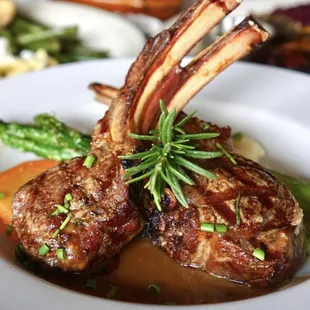 a plate of lamb chops and vegetables