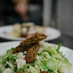 a plate of salad with fried fish