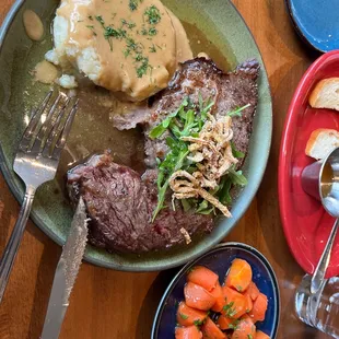 a plate of steak, mashed potatoes, carrots, and gravy