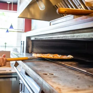 a man taking a pizza out of the oven