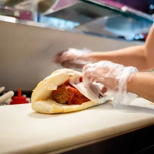 a person preparing a meatball sandwich