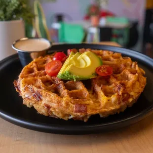 a waffle with bacon, avocado, and tomato
