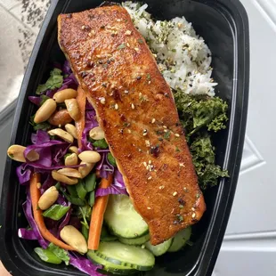 Asian inspired salmon with steamed rice, fresh cucumber slices, roasted kale, and a Asian salad
