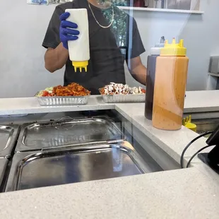 a man in a kitchen with a bottle of ketchup