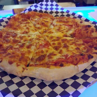 a cheesy pizza on a checkered paper plate