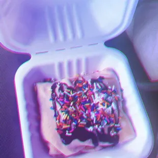 a piece of cake with sprinkles in a plastic container