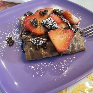 a plate of waffles with strawberries, chocolate and powdered sugar