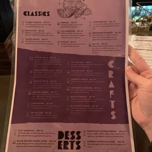 a person holding a cocktail menu