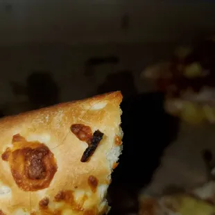 a hand holding a piece of pizza