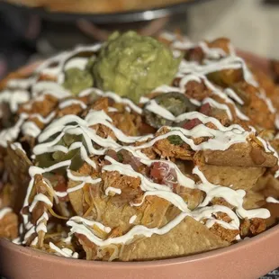 a plate of nachos with sauce and guacamole
