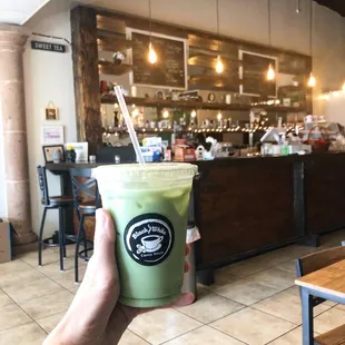 a hand holding a green drink