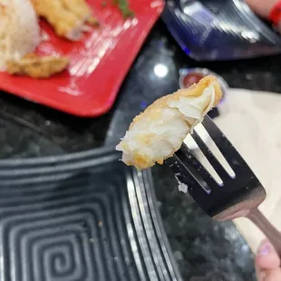 a person holding a fork with a piece of fried food on it