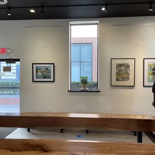 a woman looking at paintings on a wall