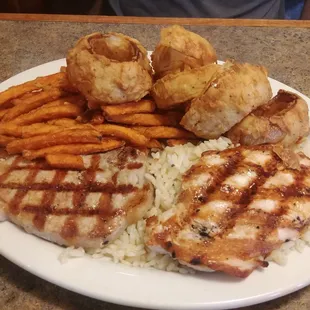 Pork chops, rice, onion rings, and sweet potato fries