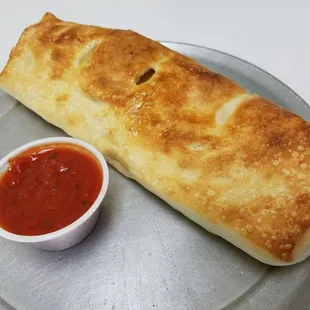 a burrito and a bowl of ketchup