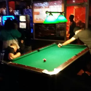 two men playing pool in a bar