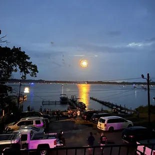 a full moon rising over the water