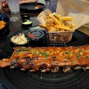 ribs and fries on a black plate