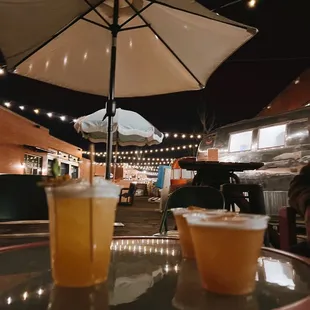 two cups of beer on a table under an umbrella
