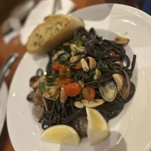 a plate of pasta with clams and a slice of lemon