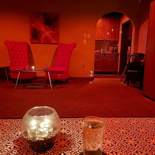 a living room with red chairs and a glass of wine