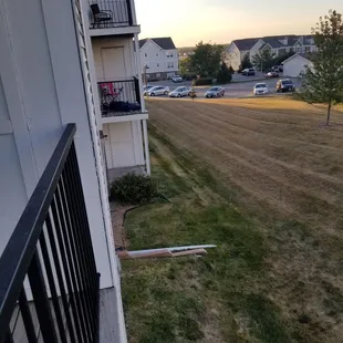 Vagrant harbored by neighbor sleeping in sleeping bag on balcony.