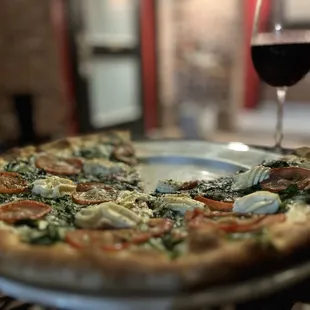 Pizza and glass of Cabernet in the courtyard. Spinach, Tomatoes, Garlic, and Ricotta pizza.