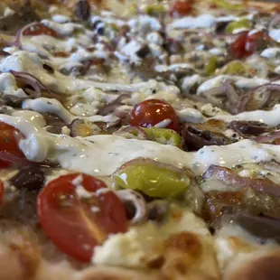 Gyro Pizza. Beef and lamb gyro meat, tomatoes, red onions, kalamata olives, pepperoncini, and feta with a tzatziki drizzle.
