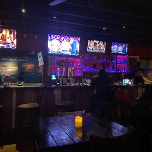 people sitting at a bar watching televisions