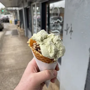 a hand holding a cone of ice cream