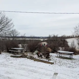 a snow covered yard with picnic tables and benches