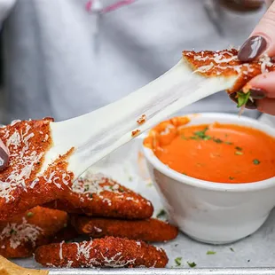 a woman dipping sauce on a stick