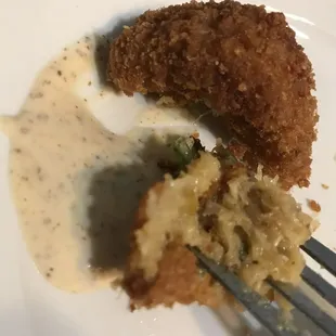 a piece of breaded and fried food on a white plate with a fork