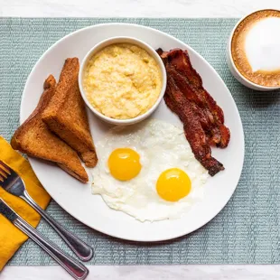 a breakfast plate with eggs, bacon and toast