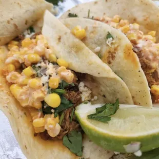 two tacos with corn and a lime