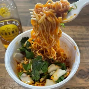 a bowl of noodles and a bottle of beer