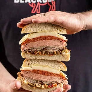 a man holding a stack of sandwiches