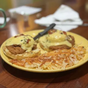 a plate of eggs benedict and hash browns