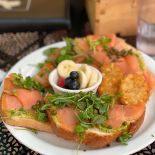 Salmon avocado toast with micro greens, hash browns and fresh fruit